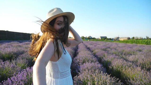 Young woman holding male hand and running through lavender field. Happy couple having fun on blooming flower meadow. Smiling girl jogging looking back into camera. Nature landscape. POV Slow motion