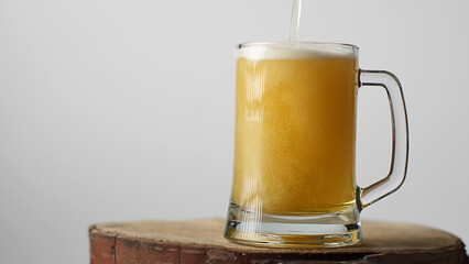 Beer is poured into a beer glass with a handle, a lot of bubbles and foam that flows down the glass.