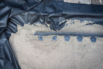 Landscape fabric for weed protection under the level sand layer of sidewalk project with plastic...