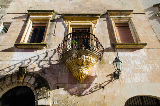 Il balcone con la ringhiera in ferro battuto e i fregi in pietra leccese in un palazzo storico di Corigliano d'Otranto