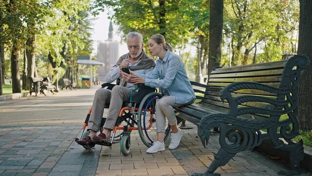 Disabled senior man watches taken photos with daughter