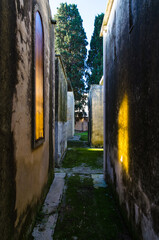 La luce del sole attraversa una finestra gialla e si riflette sul muro di fronte in un piccolo viale del cimitero di Tricase, borgo del Salento in Puglia