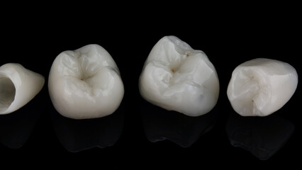 macro dental photo of ceramic crowns of chewing teeth on black glass with reflection