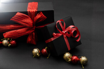black gift box, balls, red Christmas decorations on the dark wooden background copy space