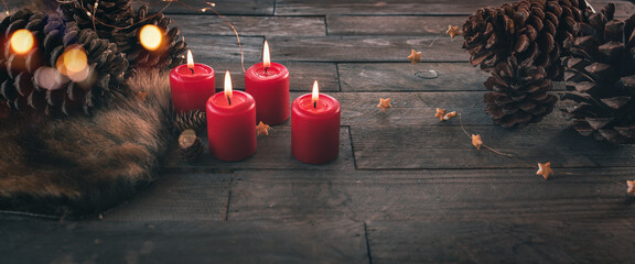 Four burning red christmas candles with golden bokeh, festive dekorated on dark wood with fairy...