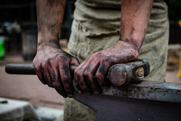 Dirty hands of blacksmith holding a hammer - 532173686
