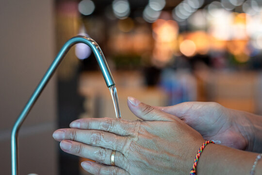 Mujer lavandose las manos en terminal de higiene de un aeropuerto. Fotografía con enfoque selectivo