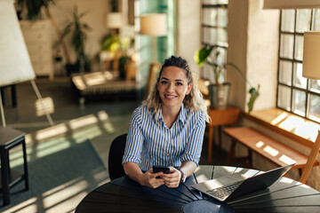 Portrait of a smiling businesswoman, chatting with someone while being at the office.