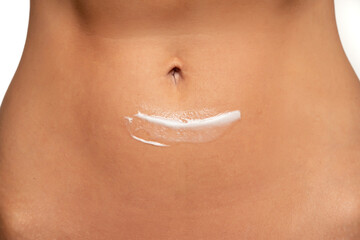 Close-up partial view of woman posing with body cream on belly - obrazy, fototapety, plakaty