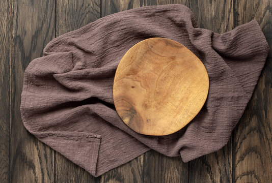 Empty wooden irregular plate on wooden oak kitchen table, top view, flat lay. Food background with copy space