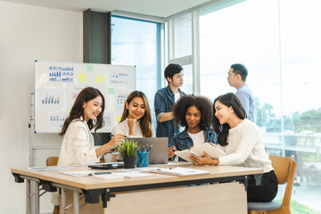 Young and successful mixed race, asian business people working on project together, sitting at table in boardroom.