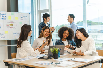 Young and successful mixed race, asian business people working on project together, sitting at table in boardroom.