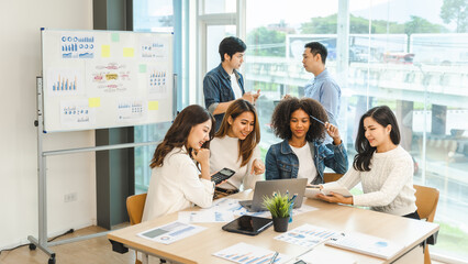 Young and successful mixed race, asian business people working on project together, sitting at table in boardroom.
