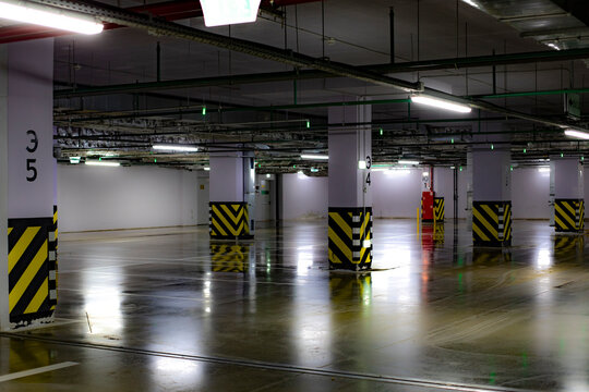Parking area in the basement, white columns with a striped base, empty parking
