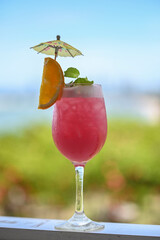 Fresh Red and blue Fruit Punch beverage with orange slices in Wine glass on blurred nature Background 