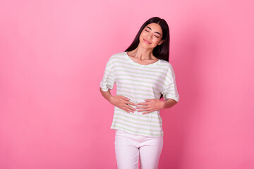 Photo of adorable satisfied person closed eyes arms touch stomach isolated on pink color background