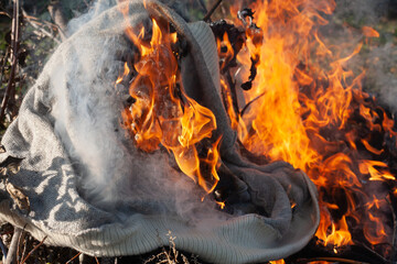 A hole in the knitted fabric. Burning old clothes after an infectious disease