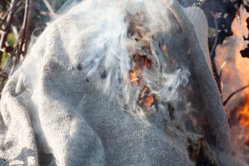 A hole in the knitted fabric. Burning old clothes after an infectious disease