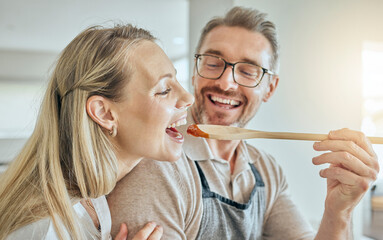 Happy couple cooking, tasting spoon of food and meal, lunch and dinner in kitchen at home. Smile...