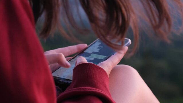 Close up of a dark-haired girl in a red sweatshirt chatting on the mobile