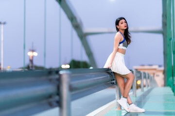 Portrait of beautiful athletic young asian woman in fashionable sportswear standing and having rest after exercise training on Route walking jogging or ride bicycle and exercise on the bridge.