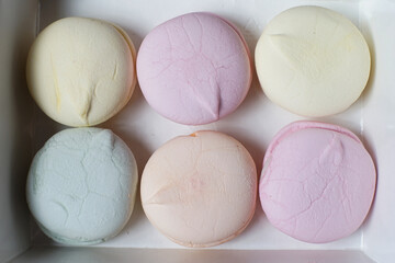 Six colorful handmade marshmallows in a cardboard box on the table