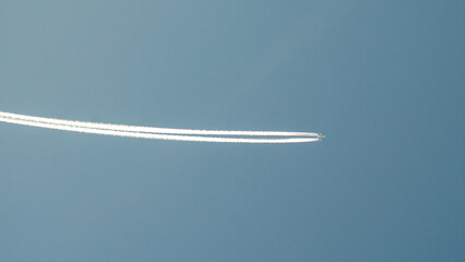 Airplane with a long reverse trail in the blue sky