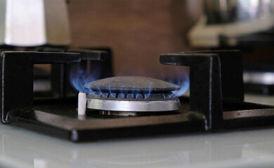 Fototapeta na wymiar Close-up blue flames of fire on a gas burner in the kitchen for cooking. Gas flame in a gas boiler.