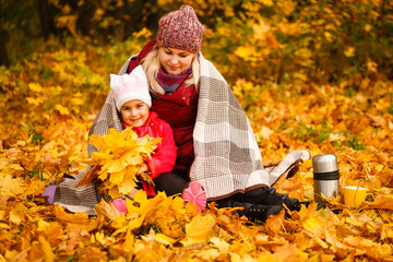 Mom and her daughter spending weekend, picnic in the autumn forest together. Mother and child relations.