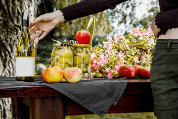 Butelka wina na stole z pustą etykietą, owoce sezonowe zerwane z drzewa, wino z jabłek, cydr, wino musujące, napoje z jabłek - obrazy, fototapety, plakaty