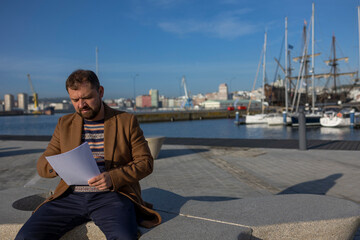 A businessman sits with documents in the port.
