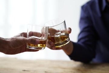 Businessman handshake after make deal, alcoholism, alcohol addiction and people concept - male alcoholic with glass of whiskey lying or sleeping on table 