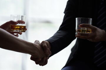 Businessman handshake after make deal, alcoholism, alcohol addiction and people concept - male alcoholic with glass of whiskey lying or sleeping on table 