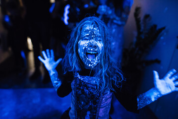 Portrait of a smiling girl at a children's party. Fluorescent paint on the face in ultraviolet...