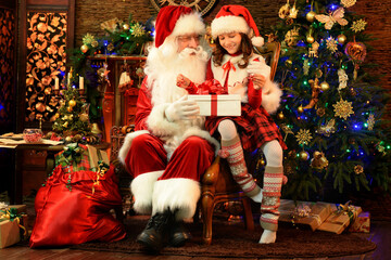 Fototapeta na wymiar Santa Claus in a traditional costume with a girl in a room