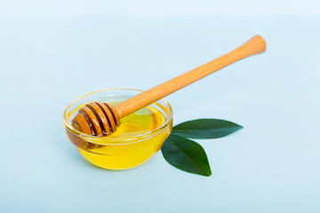 Honey in jar with leaves and honey dipper on colored background top view with copy text