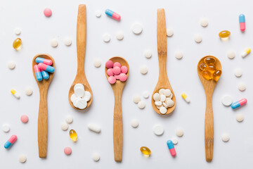 Vitamin capsules in a spoon on a colored background. Pills served as a healthy meal. Red soft gel vitamin supplement capsules on spoon