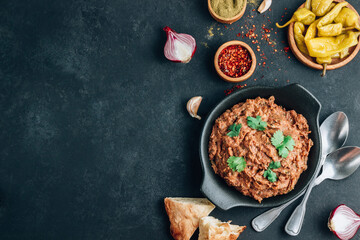 Mashed red bean with spices. Traditional georgian dish lobio in black plate with bread and pickled hot peppers.