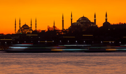 The view of the Blue Mosque and Hagia Sophia at sunset and after sunset was photographed with a...
