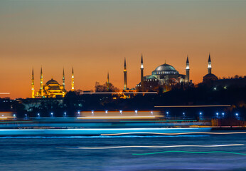The view of the Blue Mosque and Hagia Sophia at sunset and after sunset was photographed with a...