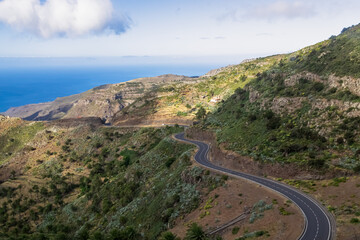 Fototapeta na wymiar Panoramic curvy mountain road on the way to Valle Gran Rey, La Gomera, Canary Islands, Spain, Europe. Scenic view on the Atlantic Ocean and hills with palm trees. Remote peaceful and silent location