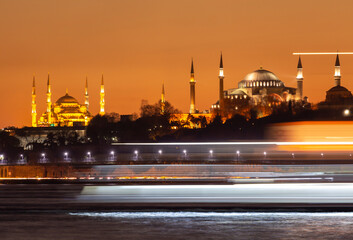 The view of the Blue Mosque and Hagia Sophia at sunset and after sunset was photographed with a...