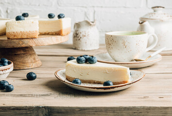 Cheesecake with blueberries on white plate. Classical New York cheesecake. Wooden background