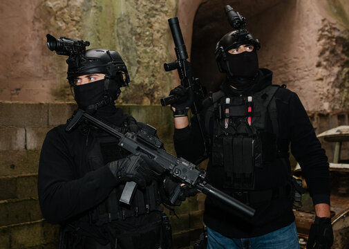 Anonymous squad fighters with rifles aiming near shabby building