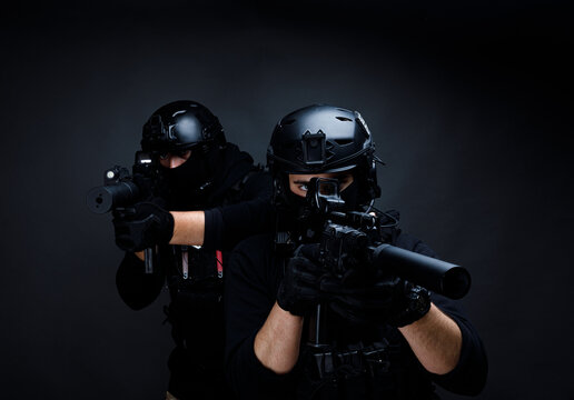 Attentive male warriors with rifles aiming in dark room