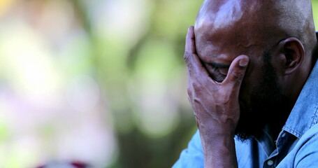 Worried African man covering face with hand having difficulties