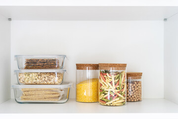 food containers and glass jars with products on white shelf at kitchen