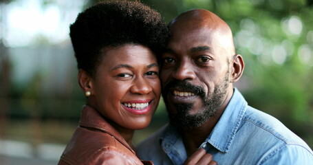 Woman kissing man in cheek, African couple romance outside at park