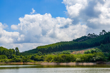 View of blue sky, white clouds and green hills and forest at outdoor reservoir