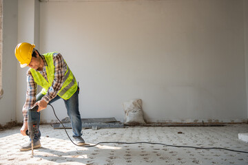 Construction worker Using an electric jackhammer to drill perforator equipment making holes before...